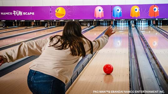 Girl throwing red bowling ball down a bowling lane at namco funscape