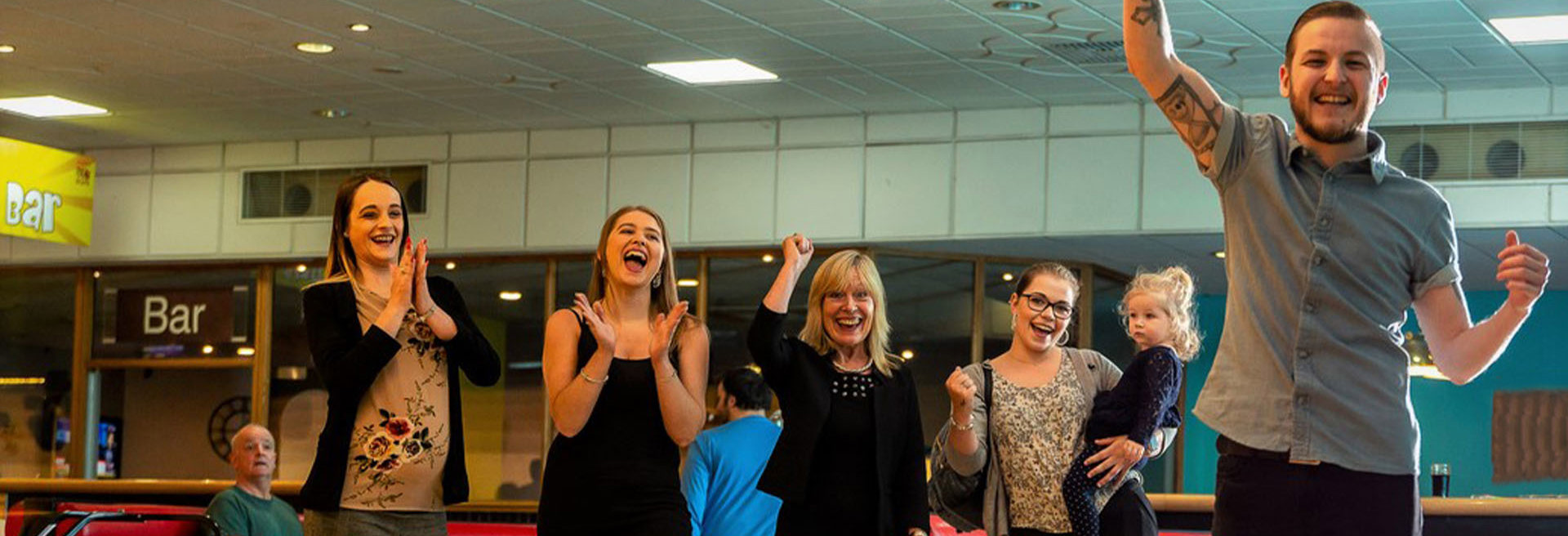 Group of friends cheering whilst playing a game of bowling