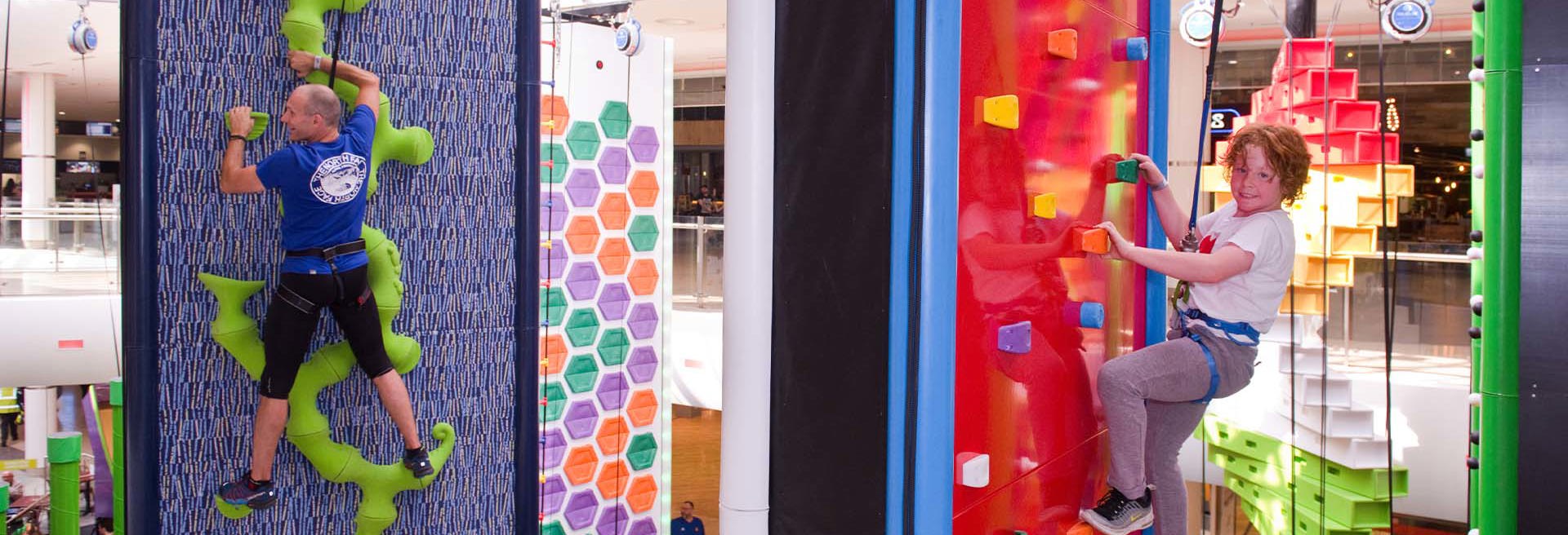 Older male and young girl climbing on clip n climb walls