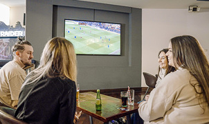 Group of friends having a drink and socialising whilst watching football 