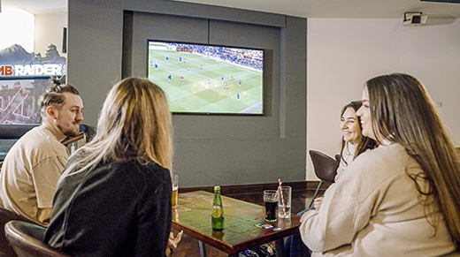 Group of friends having a drink and socialising whilst watching football 