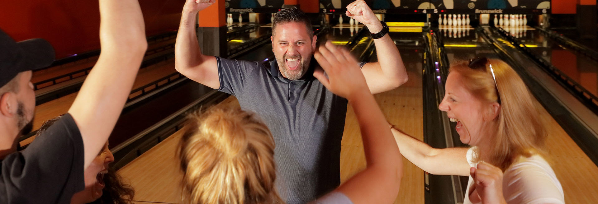 Energetic group of people cheering and celebrating at the bowling alley