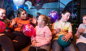 Cheerful group of children celebrating at a birthday party, surrounded by baloons and decorations, smiles, and excitement
