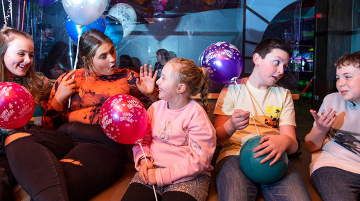 Cheerful group of children celebrating at a birthday party, surrounded by baloons and decorations, smiles, and excitement