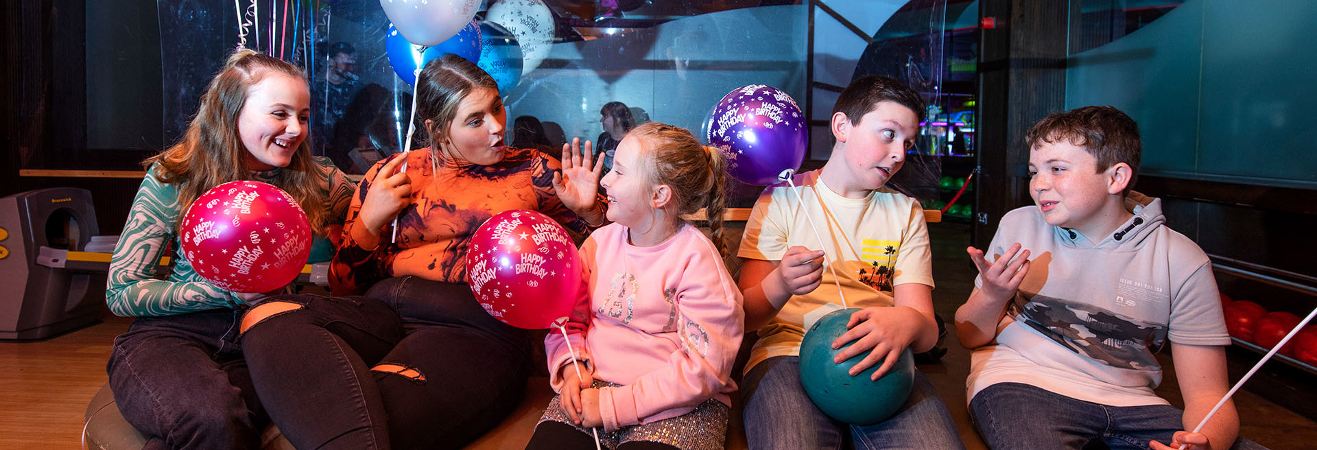 Cheerful group of children celebrating at a birthday party, surrounded by baloons and decorations, smiles, and excitement