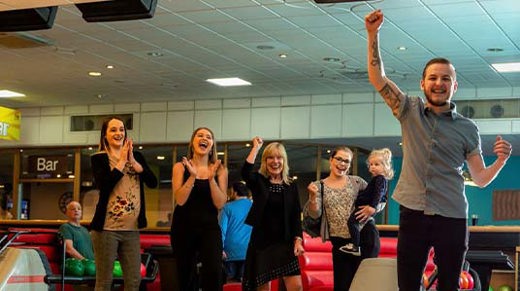 Group of friends cheering whilst playing a game of bowling