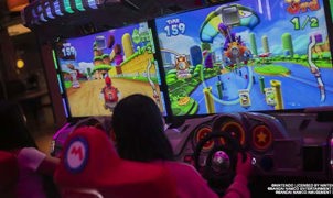 Two girls playing mario cart driving arcade game at namco funscape