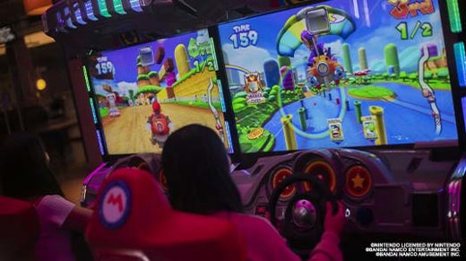 Two girls playing mario cart driving arcade game at namco funscape