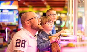 Father and children gazing up at claw machine