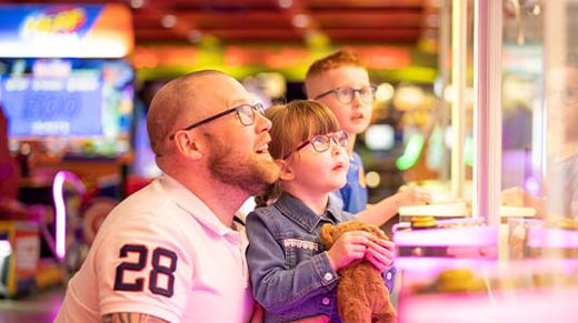 Father and children gazing up at claw machine